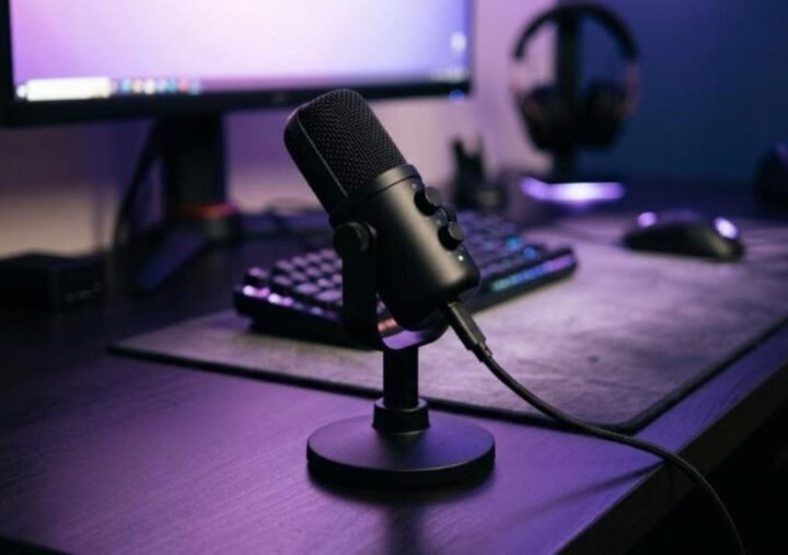 HyperX SoloCast style compact black USB condenser microphone on a gaming desk with purple ambient lighting