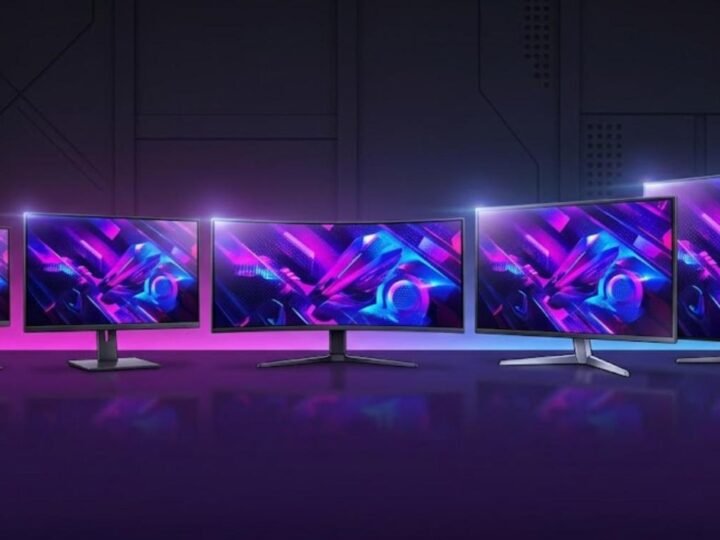 Illustration of five glowing OLED gaming monitors in different sizes lined up on a dark purple desk, from a small 27-inch screen to a large 42-inch display
