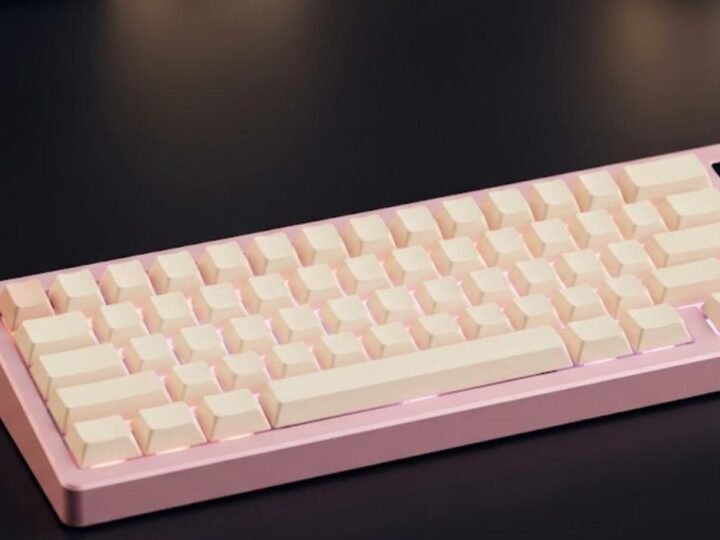 Pink and cream YUNZII IF68 style 65% wireless mechanical keyboard with a small color screen and a gold knob in the top right corner on a dark desk